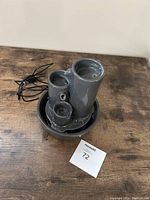 Grey ceramic electric fountain from side angle showing three cylindrical tiers in round base with attached black power cord.