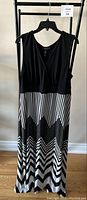 Front view of the full maxi dress hanging, showing black sleeveless top and black and white zigzag patterned skirt.
