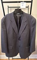 Front view of dark gray men's suit jacket with two buttons and notch lapel on hanger.
