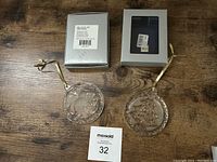 Photo of both crystal ornaments with their original boxes on a wooden surface with MaxSold numbered card