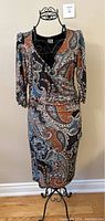 Full front view of the paisley wrap style dress on a black mannequin with a plain wall background.