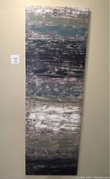 Front view of tall modern acrylic painting with abstract textured strokes in dark and muted colors hung on wall.