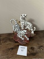 Figurine showing front and side view of two white tigers on rose crystal cluster base.