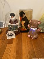 Overall view of knickknacks including Eskimo doll, penguin plush, bear figurine, and coasters