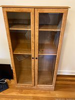 Front view of the bookshelf showing two glass doors and three interior shelves.