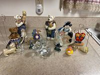 Figurines displayed on a kitchen counter including teddy bears, glass animals, a rubber duck, and other items.