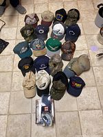 Top-down view showing all 19 hats arranged on the floor including sports, camo, and character hats.