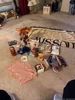 Overview photo showing most miscellaneous items spread on carpet including nesting doll, doily, figurines, keychains, and boxed items.