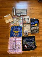 Overview photo of all memorabilia including framed prints, tapestry flags, clothing, and rolled maps