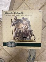 Photo of sculpture box with label showing porcelain collectible Joseph, Mary, and baby Jesus Classic Treasures sculpture