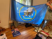 Person holding large blue Seabees flag with cartoon bee characters in center