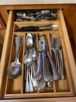 Drawer containing the Oneida silverware set, neatly organized with forks, spoons, knives, and serving utensils.