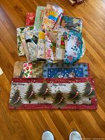 Overview of the assortment of tablecloths, placemats, and table runner spread on wooden floor showing various patterns and colors.