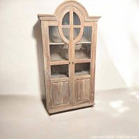 Front view of closed cabinet showing arched top and glass panel doors