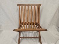 Front view of teak garden folding chair showing slatted seat and backrest with natural wood finish