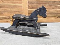 Side profile of the vintage wooden rocking horse showing the horse head detail, flat wide base, and tail detail.