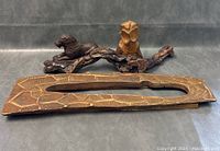 Three wooden art sculptures shown together on a plain surface, highlighting size and relative positioning.