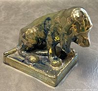 Side view of iridescent glazed Rambervilliers French pottery dog figurine, showing detail on body and base