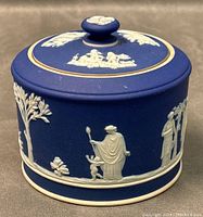 Front angled view of antique Wedgwood dark blue jasperware sugar bowl with white relief figures and foliage.