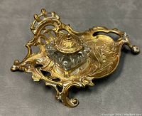 Inkwell desk set viewed from an angle showing detailed brass footed base and glass inkwell with lid in place