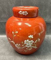 Front view of jar showing red glaze and white cherry blossom branches