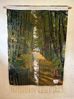 Full front view of the rectangular forest design wall hanging rug with fringe bottom.