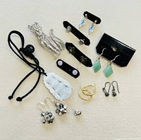 All items arranged in one photo showing the entire jewelry collection including cat brooch, jade pendant, and various pairs of earrings.