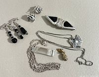Seven-piece sterling silver jewelry lot with black accents laid out on white surface