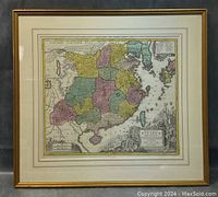 Full frontal of framed vintage map with colored provinces and decorated cartouche.