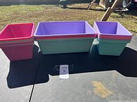 Wide shot of all bins grouped on a black surface outdoors, showcasing the colors and sizes.