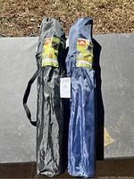 Two packed Ozark Trail folding camping chairs in black and navy blue fabric, stored in their carry bags with shoulder straps.
