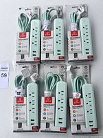Six unopened Globe Designer power strips with mint green color, braided cords, visible packaging showing brand and key features.
