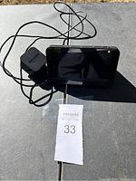 Amazon Echo Show smart display with power adapter placed on a table in natural light, showing the screen and tangled cable.