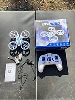 Top-down view of drone, remote controller, charger, battery and box laid out on table.