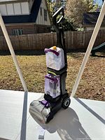 Full view of Bissell carpet cleaner upright on table with sunny outdoor background.