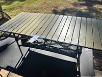 Top view of aluminum slatted camping table with mesh shelf below.