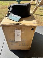 Black drawstring storage pouch containing hammock placed on a cardboard box