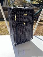 Front and side view of large travel suitcase with anchor pattern showing fabric exterior, gold zippers, and front pockets.