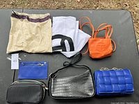 Overview of all items on dark surface including purses and cloth items