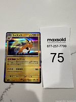 Photo showing the holographic Japanese Raichu Pokemon card with full card face visible and MaxSold lot number 75 flag next to it.