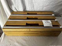 Three bamboo kitchen plastic wrap holders stacked horizontally showing the tops with attached metal cutting edges and center recessed handles.