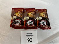 Three sealed Demon Slayer Trading Card Game booster packs with character artwork in red packaging