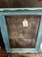 Full view of the chalk board showing the entire blue ornate frame and chalk surface with prior use marks.