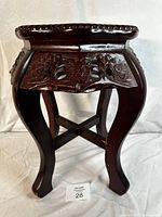 Front view of the dark wood carved legs and floral apron of the side table.