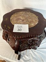 Top view of the octagonal side table with marble inset and carved wooden edge.