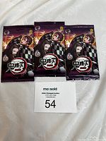 Photo showing three sealed Demon Slayer TCG booster packs with Tanjiro and Nezuko artwork.