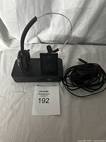 Front view of Jabra Pro headset on charging/base station with cables coiled beside