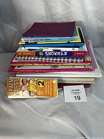 Lot of books stacked with visible titles including children's books and educational cards