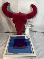 Red velvet bull skull wall decor, white ceramic candlestick holder, and framed abstract art on white background