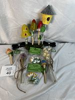 Photo showing the overall lot including colorful mushroom stakes, yellow birdhouse stake, floral accents, and black dog bone stake